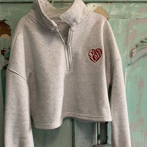 Gray long sleeve crop top with zipper and self love patch on it